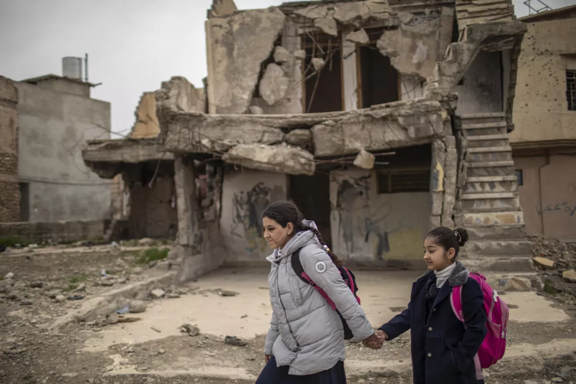 Noor (&agrave; gauche) et sa cousine, Rahaf, passent devant des immeubles effondr&eacute;s sur le chemin de l&rsquo;&eacute;cole, dans la vieille ville de Mossoul, en Iraq.