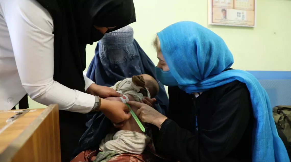 Afghanistan. Paloma looks on as a small child has her upper arm circumference measured.