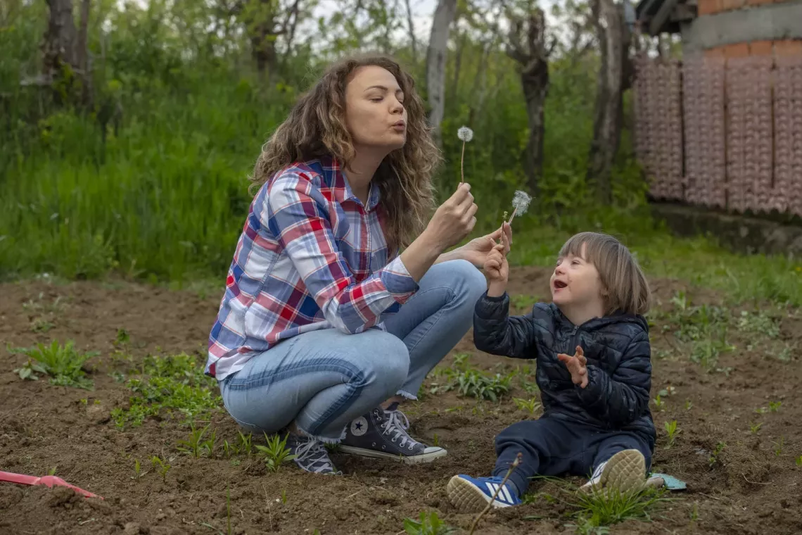 Gordana and her five-year-old son, Vuk, play with dandelions while planting vegetables in the garden of their home in Belgrade, Serbia. 