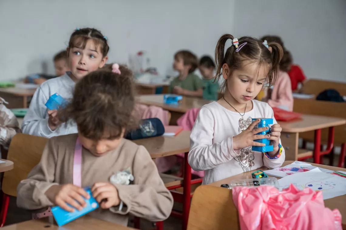 Romania. Children open blue boxes containing toy cars.