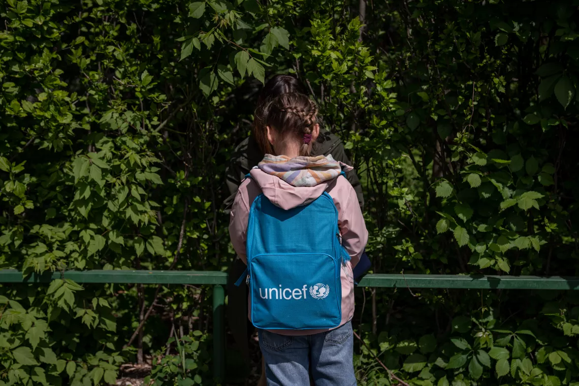 Romania. A girls carrying a backpack stands talking with a friend.