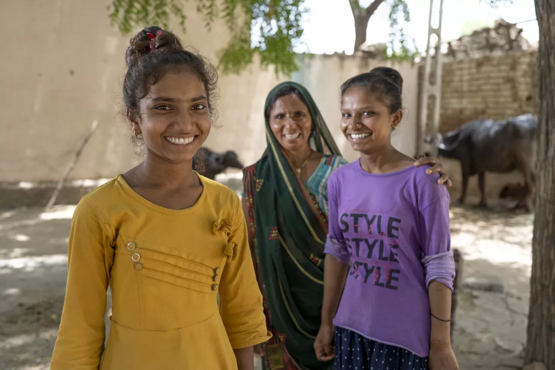 Sandhya, 15, and Asha, 17, together with their mother outside of their home in India.