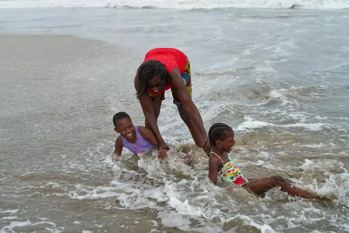 Sisters Jayda (left), 9, and Venessa, 6, play in the surf with their mother, Lucy, while spending time at the beach in Accra, Ghana. 
