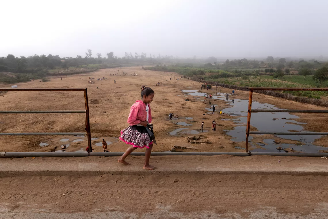 Madagascar. A child walks across a bridge over the Manabovo river in the Androy region of Madagascar. The river, pictured in August 2022, is almost completely dry, forcing people to dig holes in the ground in hopes of finding water.