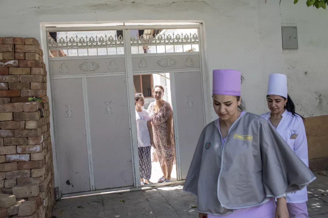 Nurse Parvina Khaydarova (front left) and Dilbar Boltaeva (front right), who is a physician, make house calls to vaccinate children in Samarkand, Uzbekistan. 