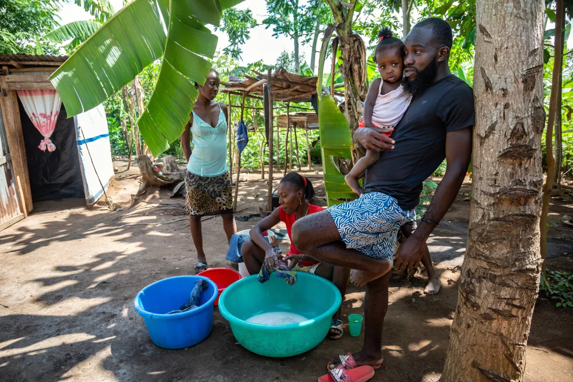 Claudy D&eacute;lice holds his daughter, Anne-Djouna&iuml;ka, in the village of Troirac.