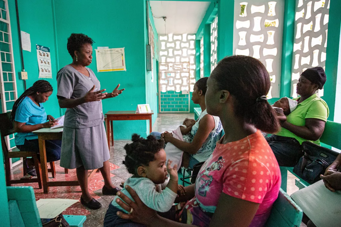 A health worker teaches caregivers about the benefits of getting their children vaccinated. 