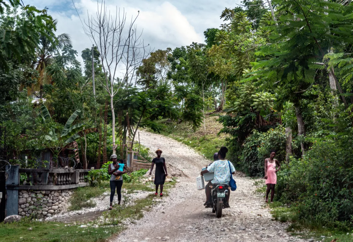 Mardoch&eacute;e Miliance sits on the back of a motorbike as she travels to the village of Troirac, where she will dispense vaccines.