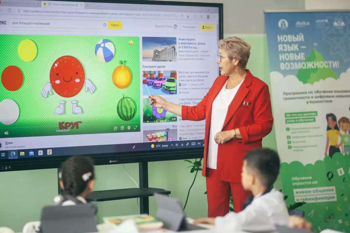 A teacher points at a television screen while conducting a lesson in Kazakhstan.