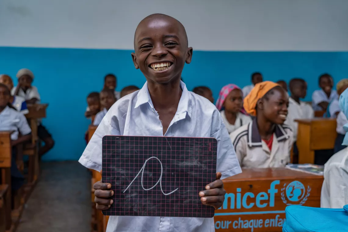 A boy holding up a chalkboard