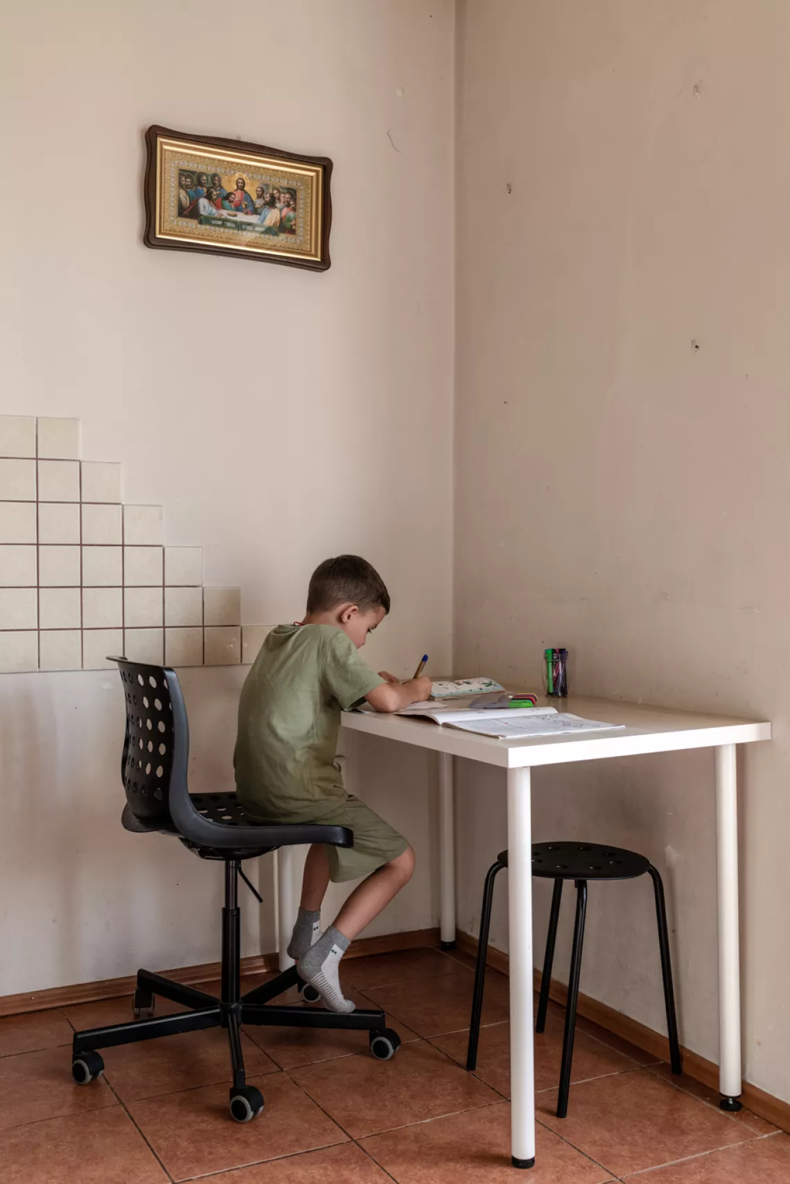 Mykyta studies at his desk at home. 