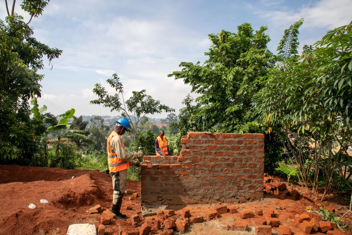 Two masons construct a new pit latrine with a bathroom in a village in Uganda.