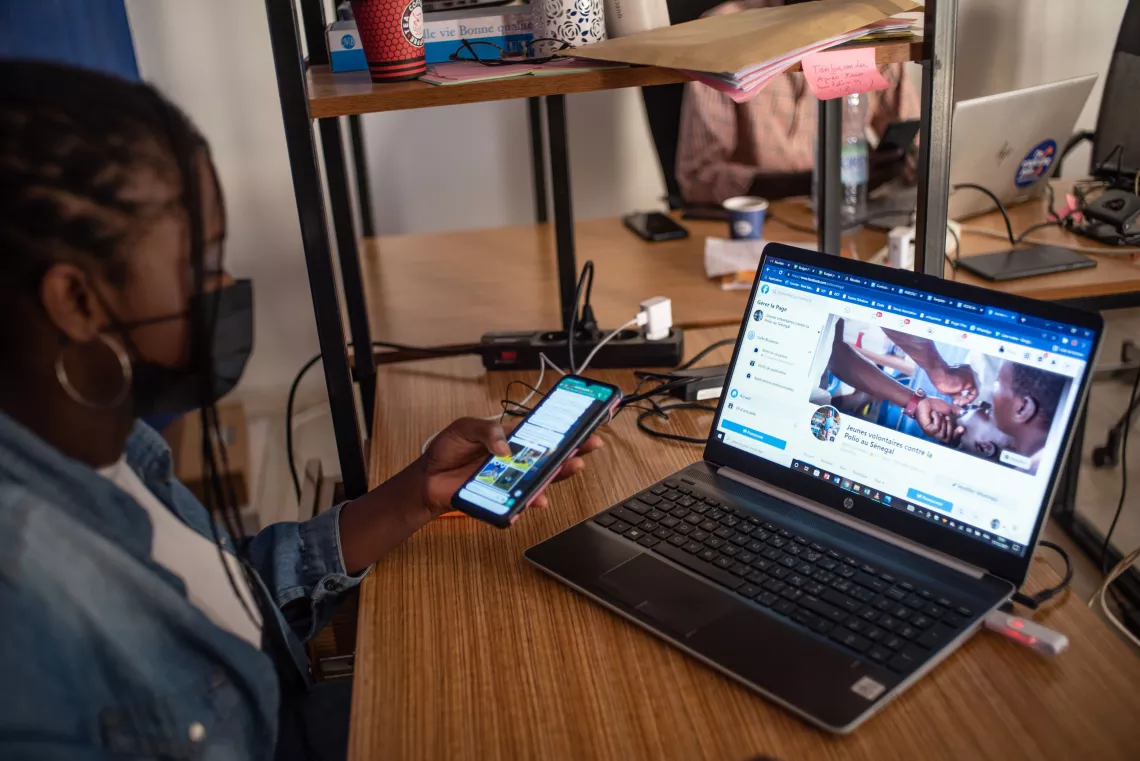 Mariama, a digital social mobilizer in Dakar, looks at her phone and laptop screens.