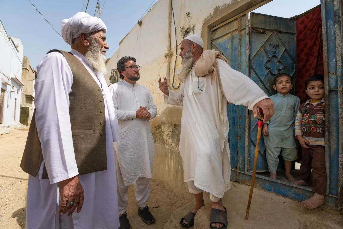 خير محمد (إلى اليسار)، زعيم قبلي لمجتمع البشتون في كراتش ، ونعيم الرحمن (في الوسط)، ناشط اجتماعي في محاربة شلل الأطفال، يتحدثان مع رب الأسرة الذي رفض لقاح شلل الأطفال لأطفاله.