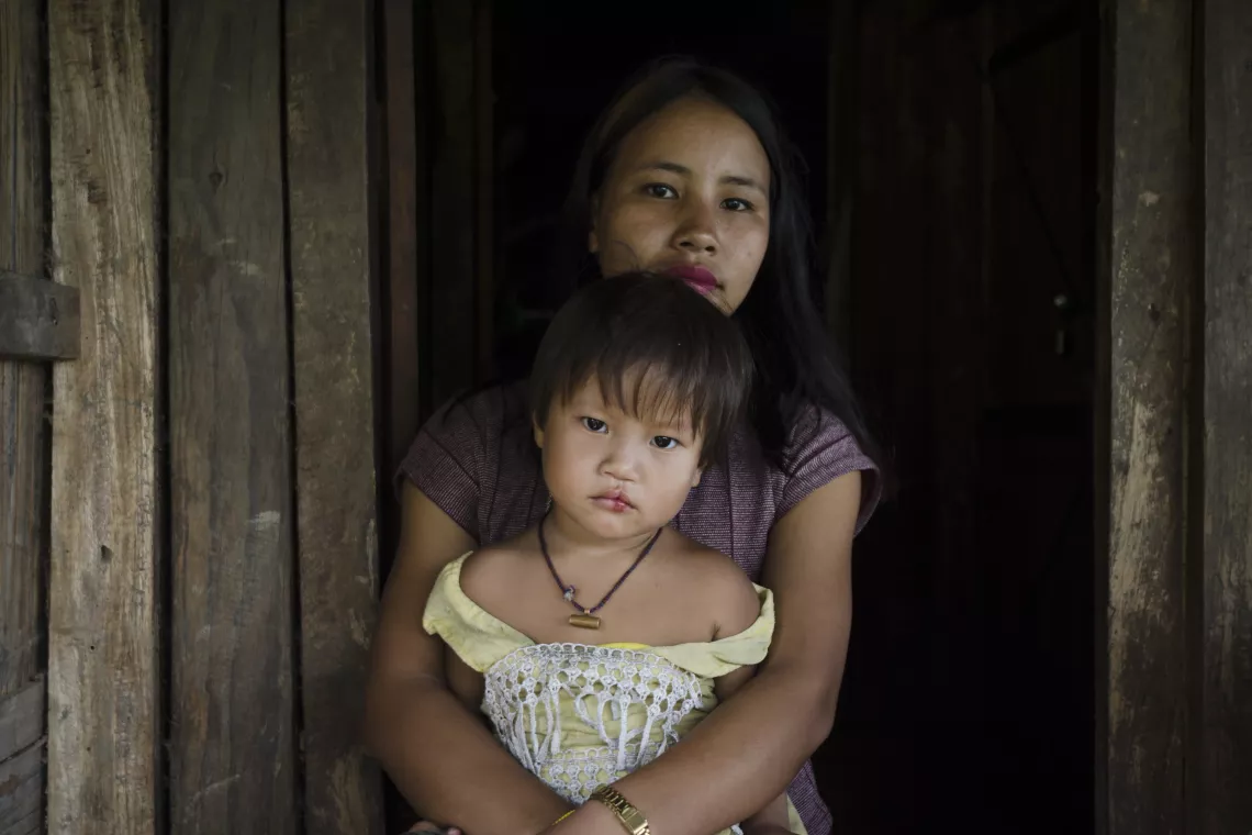 On 19 September 2022 in Khamblaiglat village, Anjaw district of Arunachal Pradesh state, India, mother Atyula Khamlai, 24, sits with her 3-year-old daughter on her lap during Village Health and Nutrition Day, an immunization and health outreach campaign.