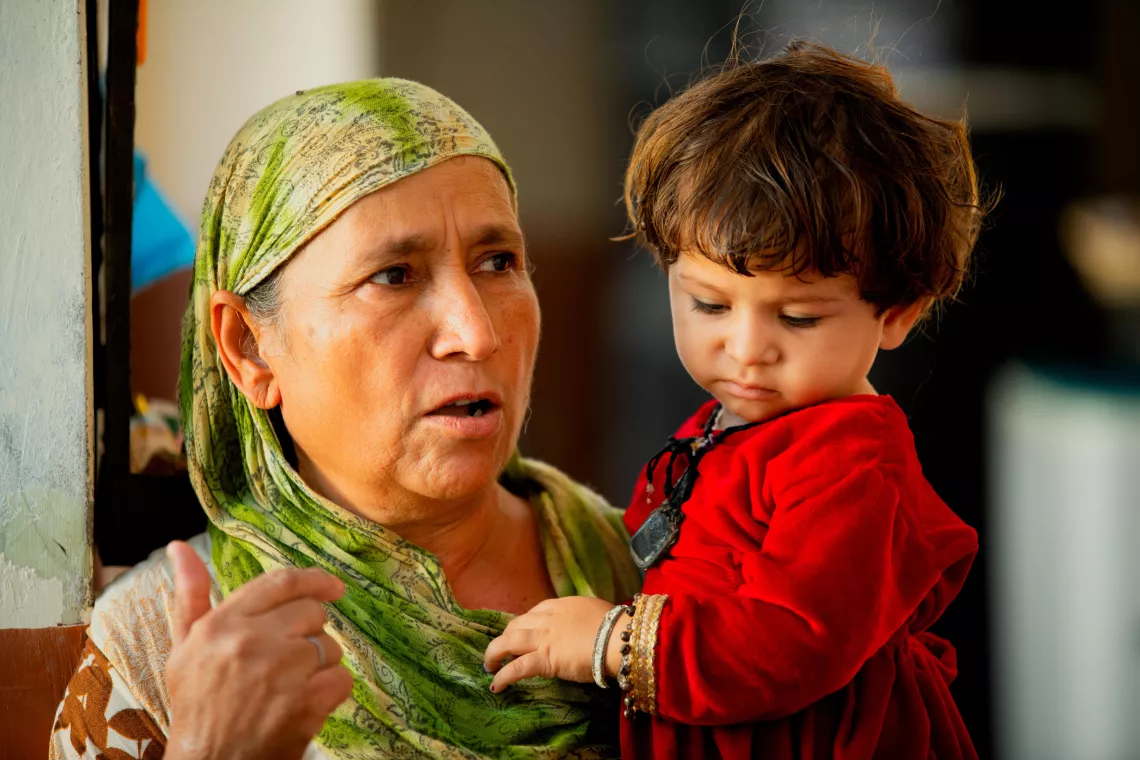 Une grand-m&egrave;re tient sa petite-fille de 18&nbsp;mois, qui vient d&rsquo;&ecirc;tre vaccin&eacute;e contre la polio.