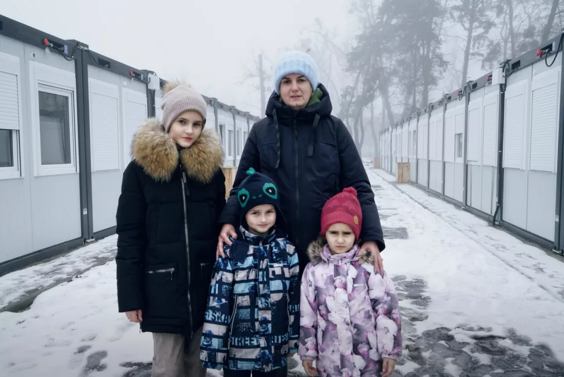 Ukraine. A family stands in the snow outside temporary housing in Irpin, outside of Kyiv.