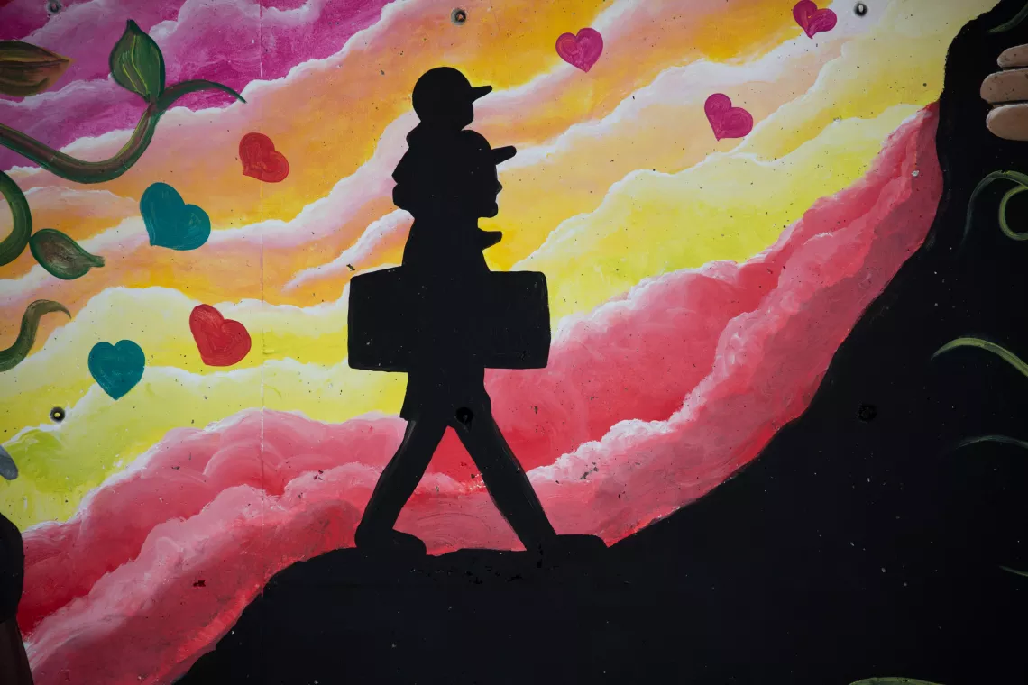 mural of the silhuette of a person carrying a suitcase and a child on his shoulders
