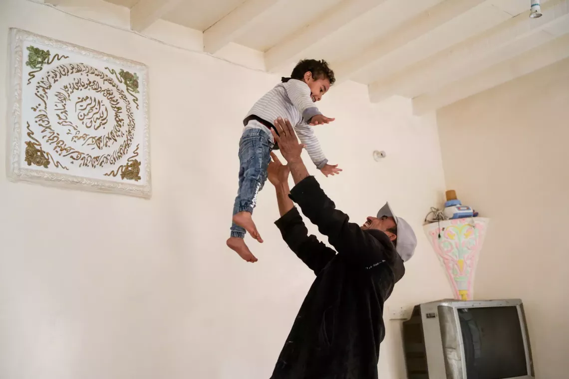 Nabil plays with his son, Mohammed, in their apartment in Dhamar Governorate, Yemen. 