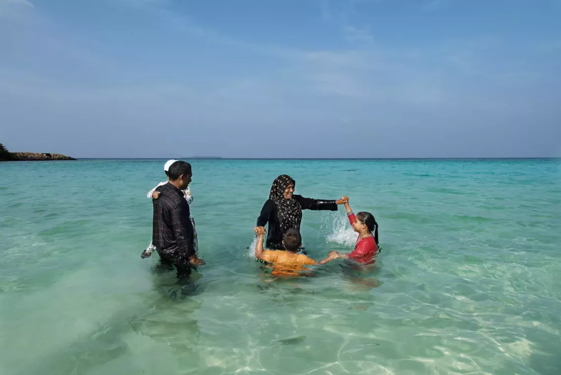 Seven-year-old Mariam and her four-year-old brother, Yusuf, play in the ocean in Milhandoo, Maldives, with their grandparents and four-year-old cousin, Arsan. 