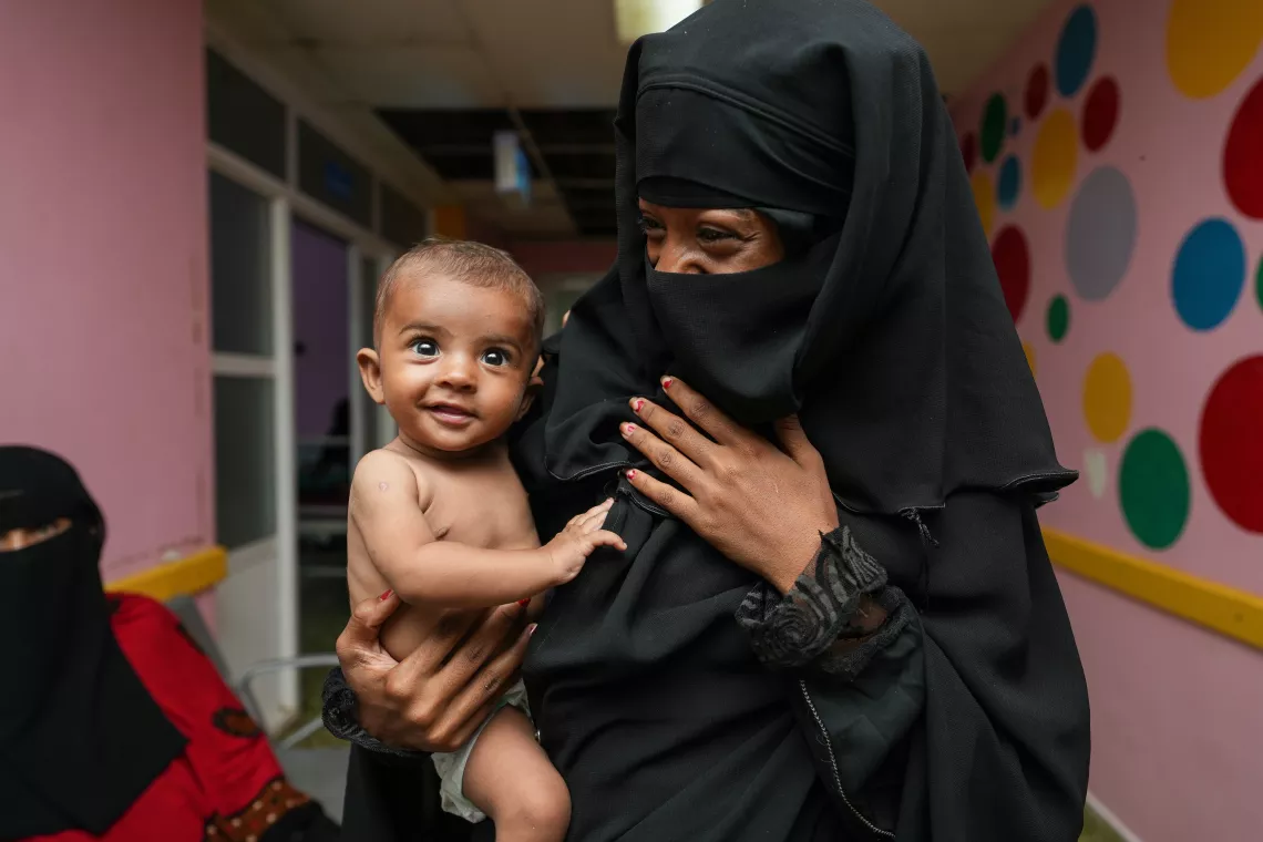 A baby boy carried by his mother.