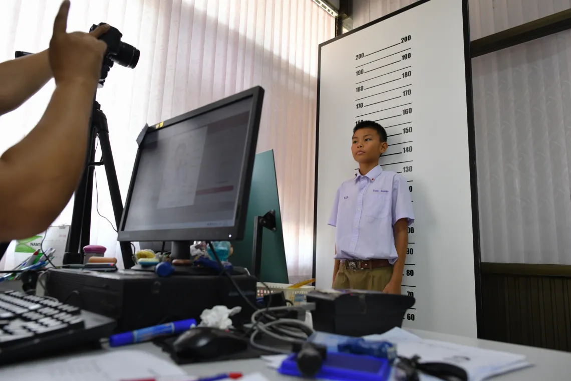 Sarm, 13, has his photo taken for an official ID card at a local government office. 