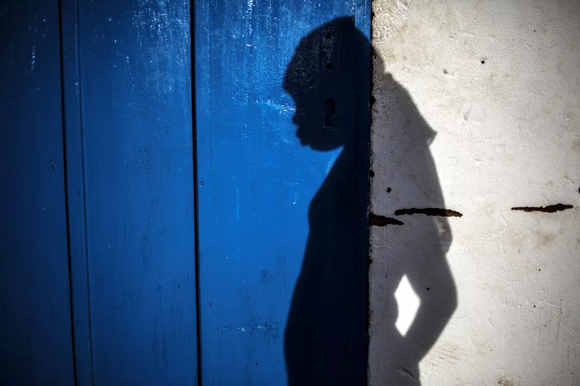 A shadow of a 16-year-old girl appears against a blue door in the Central African Republic.