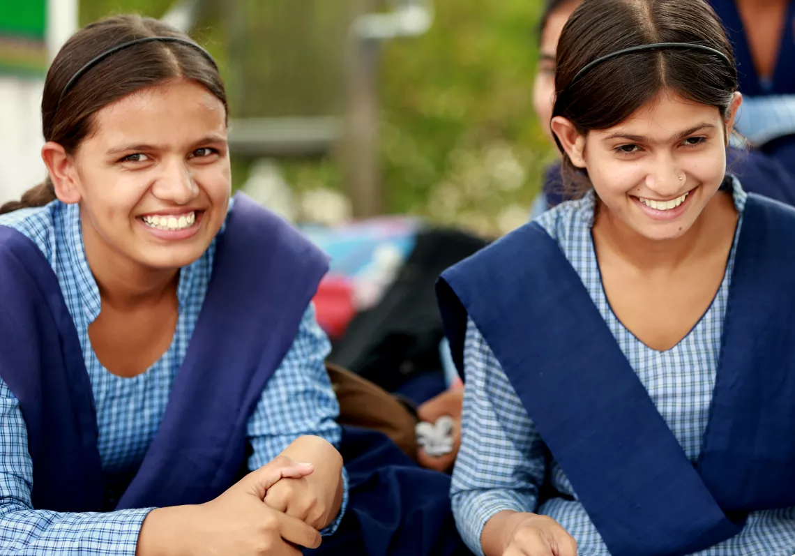 Two girls in school uniforms smile.