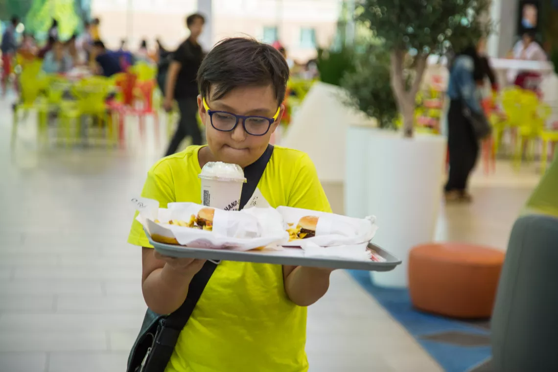 Kazakhstan. A boy carries a tray of food.