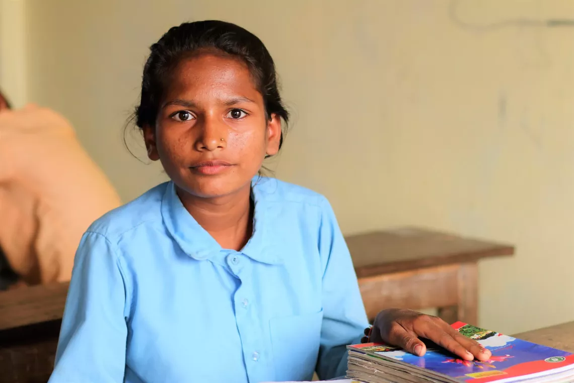 A young girl at a desk with an array of books.