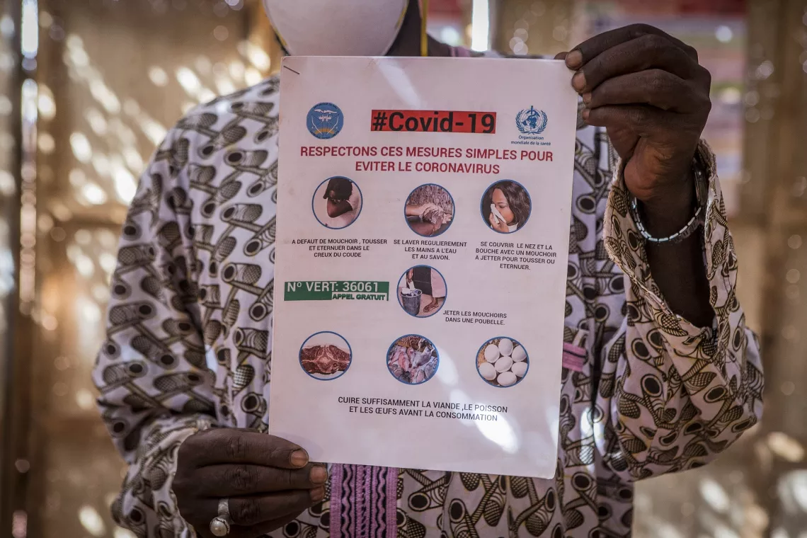 Mali. A man holds up a poster with guidance on preventing COVID-19.