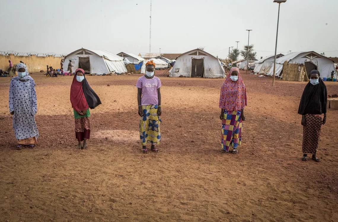 Mali. Residents at an IDP camp stand in line wearing face masks.