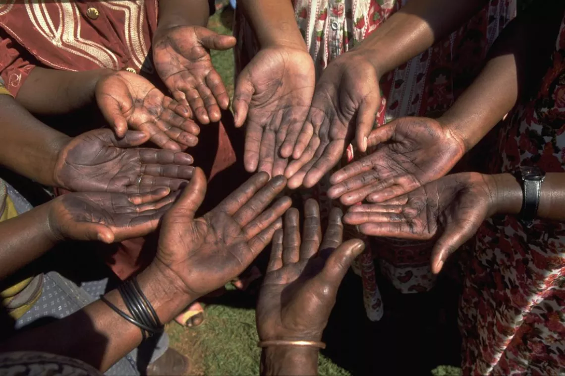 Women in a circle show the palms of their hands.