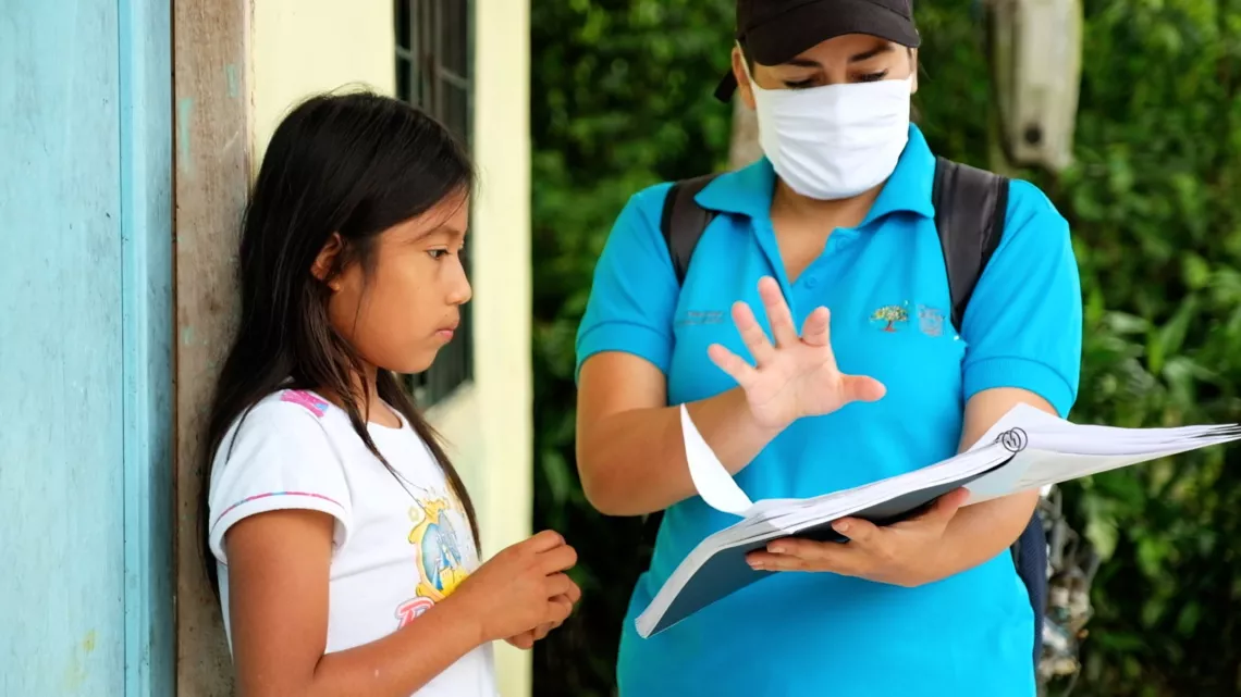 Ecuador. A teacher explains lesson materials to a girl.