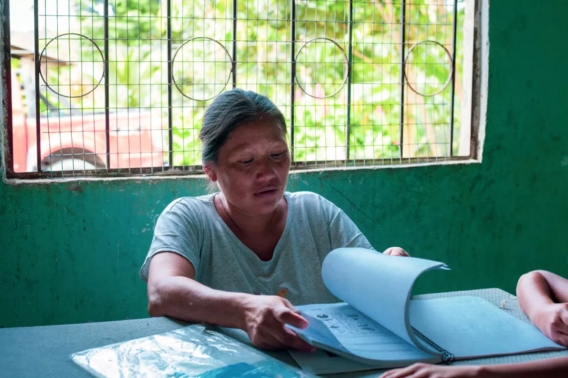 Ecuador. A woman helps her child with her homework.