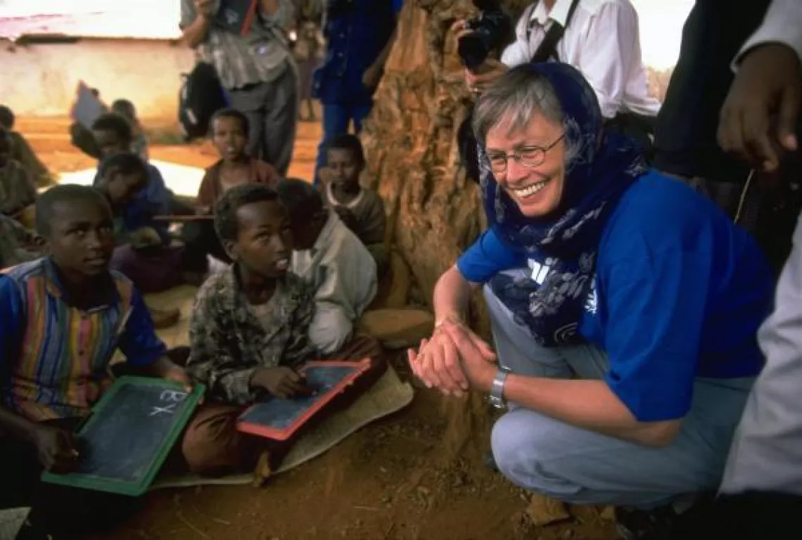 Carol Bellamy speaks with children at a school.