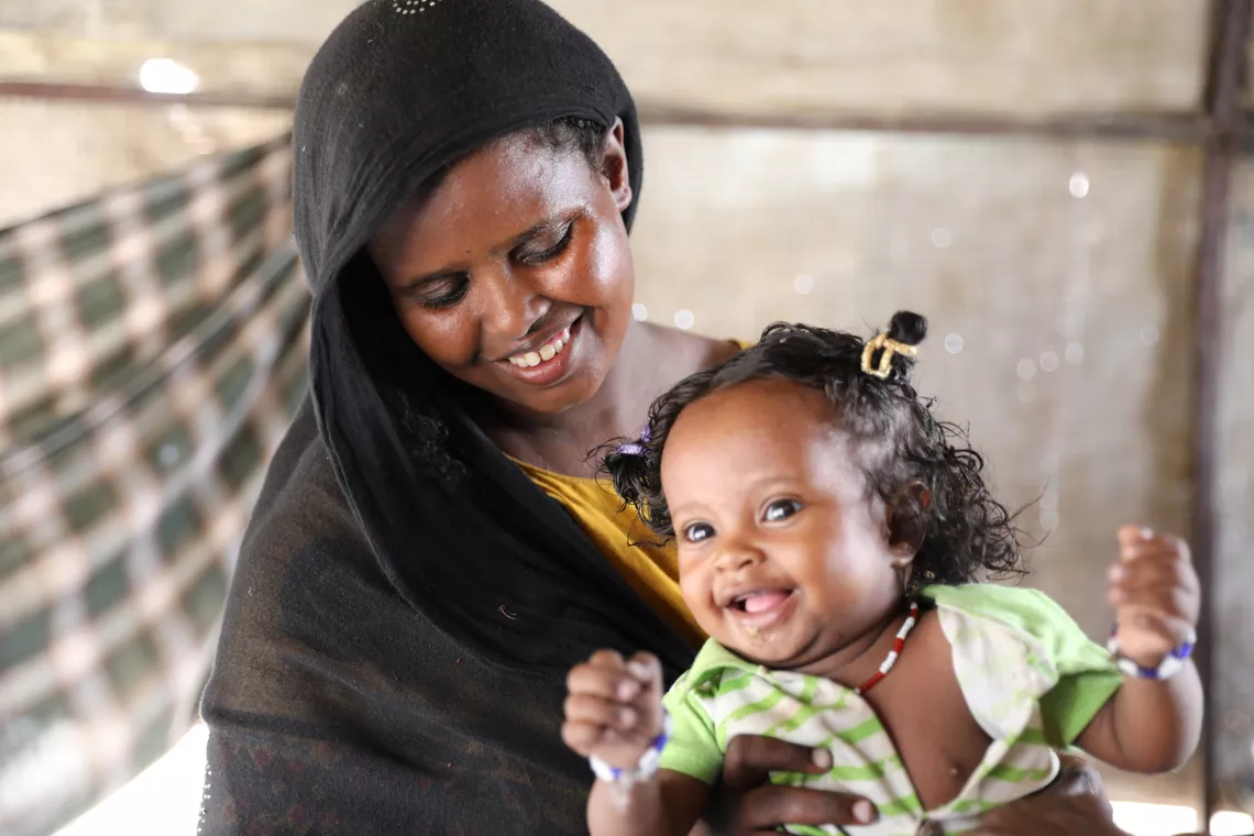 A mother and her little girl smile with joy.
