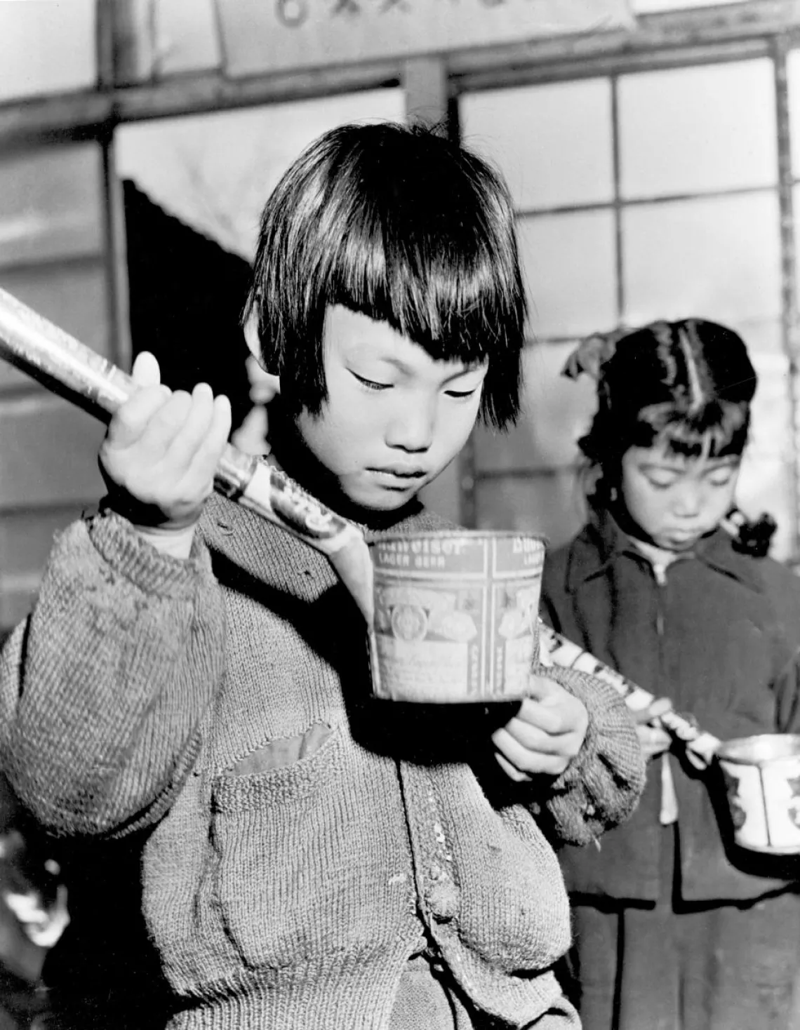 A student in Suwon, Repluc of Korea, prepares to drink her daily ration of milk.