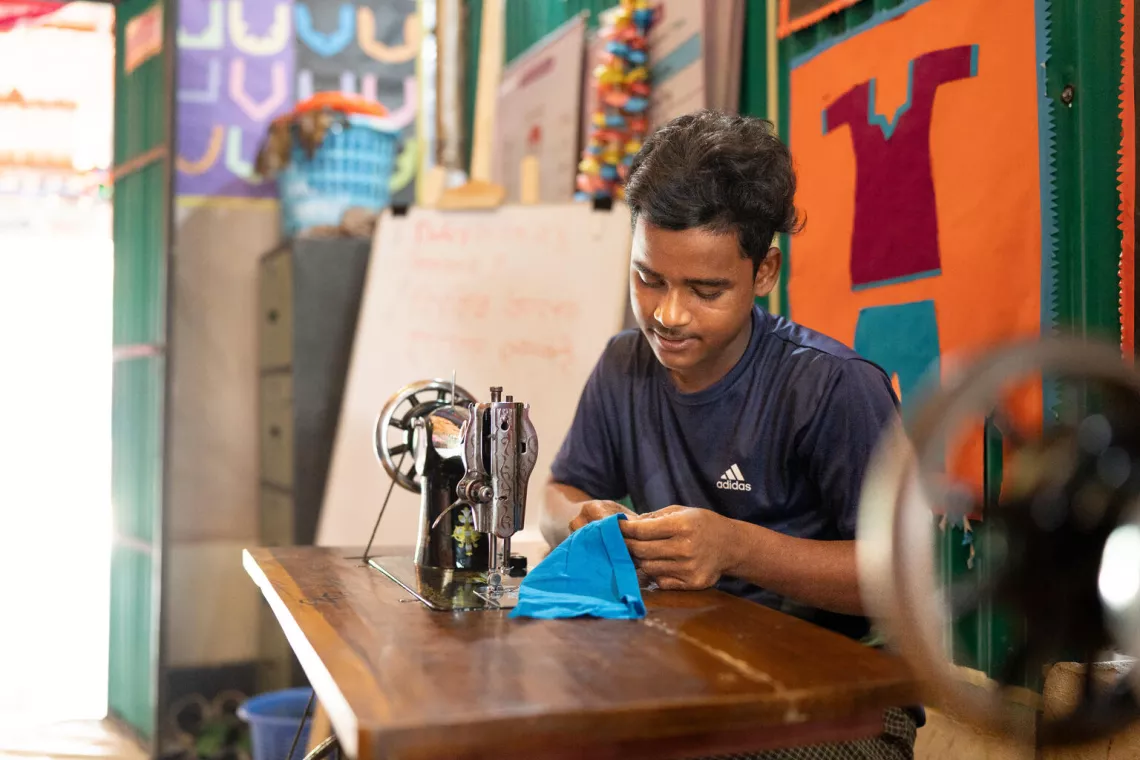 Bangladesh. Nur Kalam, 16, sews an item of clothing at a tailoring workshop at a Multi-Purpose Centre in a Rohingya refugee camp in Cox&rsquo;s Bazar