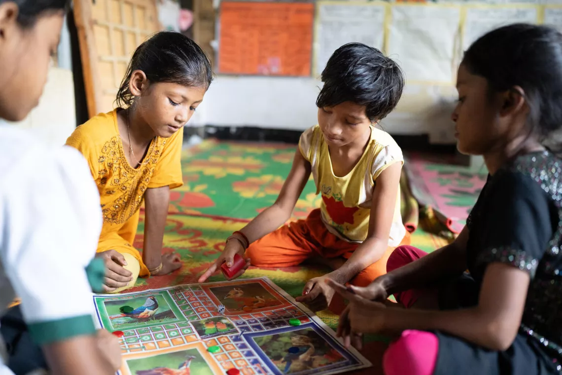 Bangladesh. A girl rolls the dice while playing a board game at a multipurpose centre.