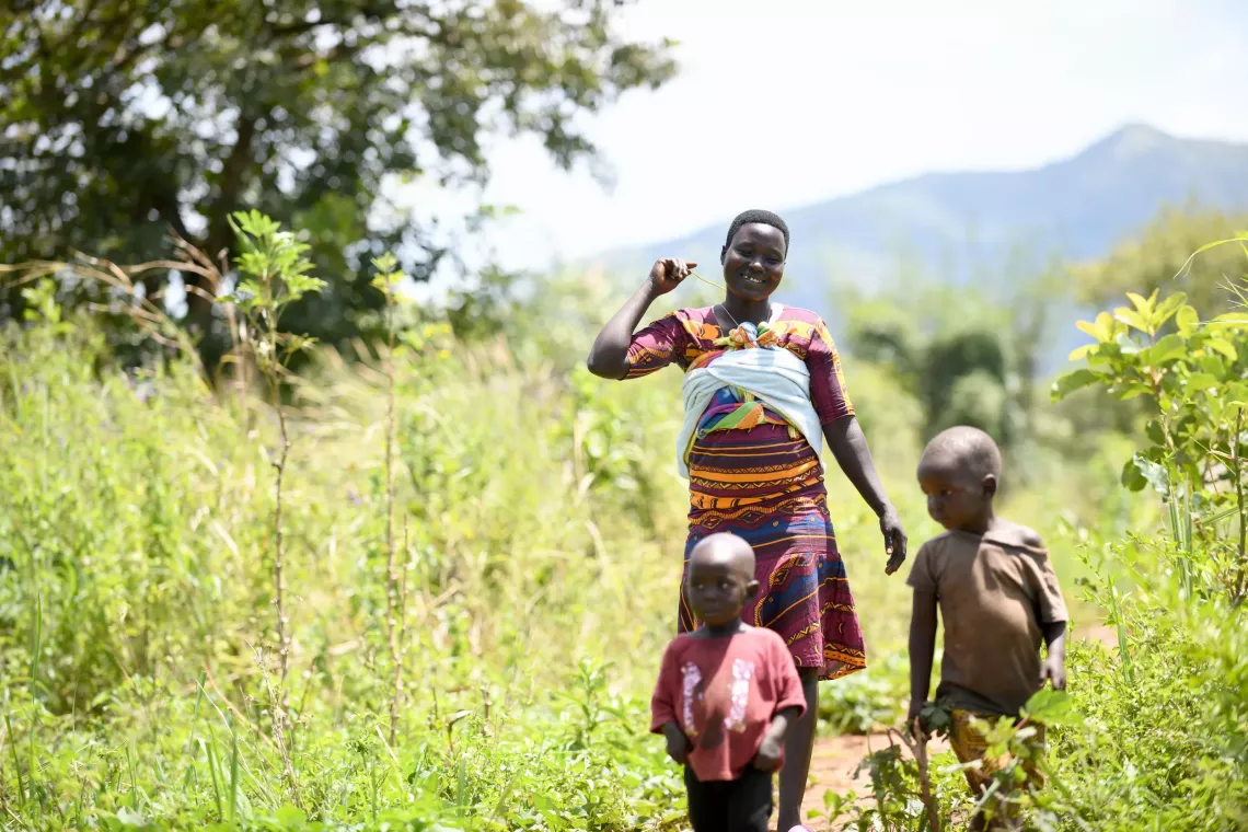 A woman and her two children walking through a field.