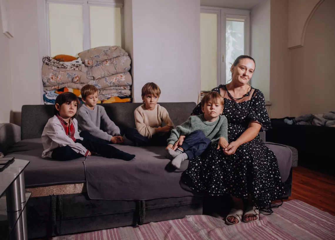 Une m&egrave;re et ses 4 enfants sont assis sur un canap&eacute; gris