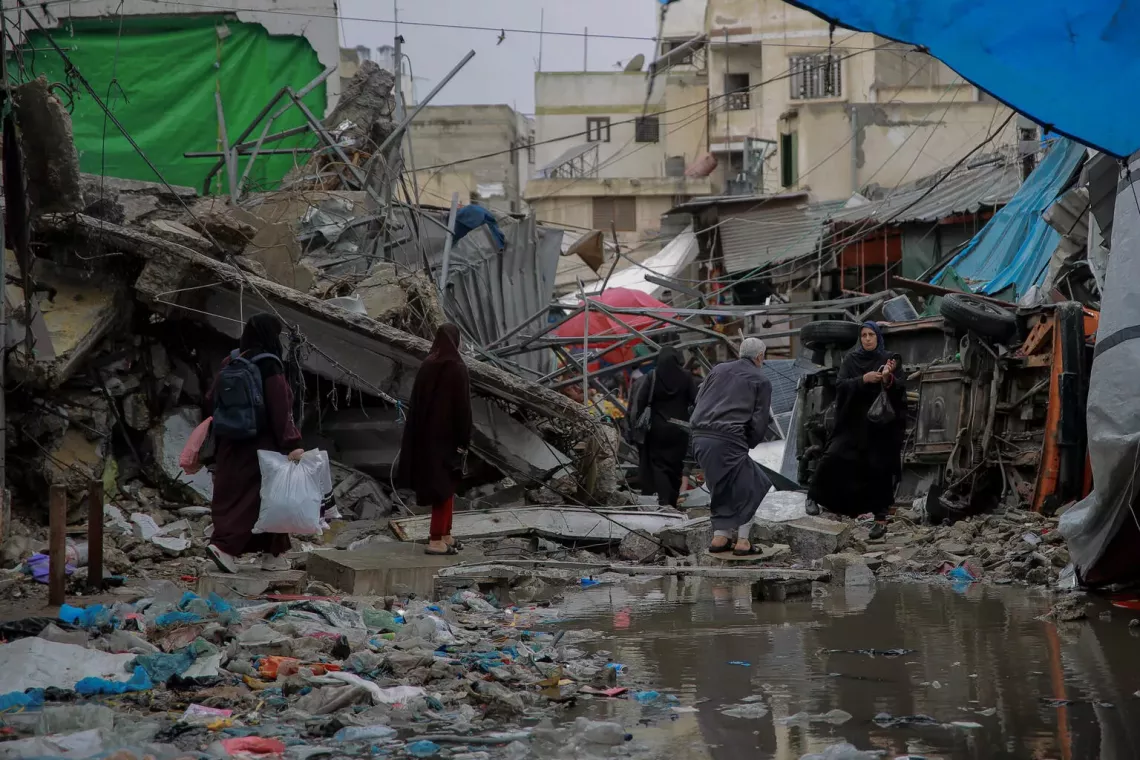 Gaza Strip. People cross the road in front of the remains of a shop destroyed in a bombardment in Azzawieh Market in Gaza City.