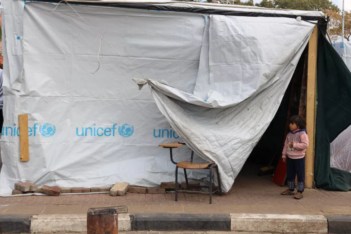 2024年1月11日，在加沙地带的一个避难中心，一个小孩站在联合国儿童基金会的帐篷旁。