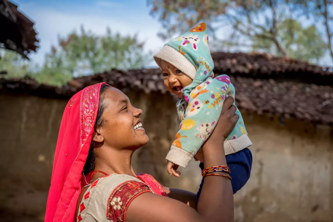 Hira holds her 11-month-old daughter, Maina, outside their home in Kanthi, India. 