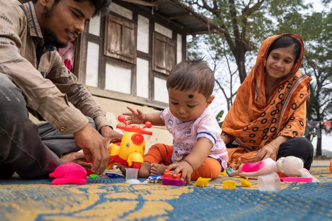 Ten-month-old Fahim and his parents play with toys in the courtyard of their home in Islamapur, Bangladesh.  