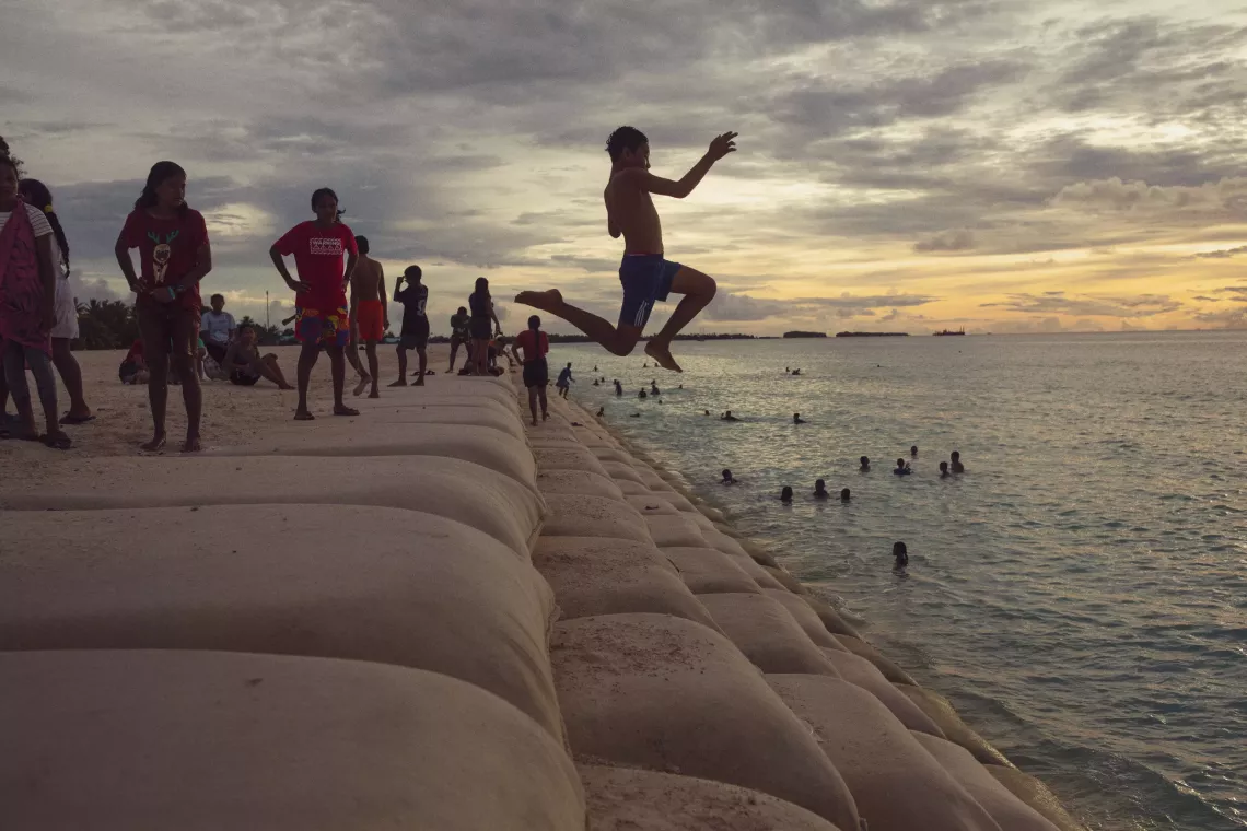 Twelve-year-old Liveti jumps from a sandbag staircase at The Reclaimed Land into the sea in Tuvalu. His leap covers 3-4 meters, with the water lying 2-3 meters below him.
