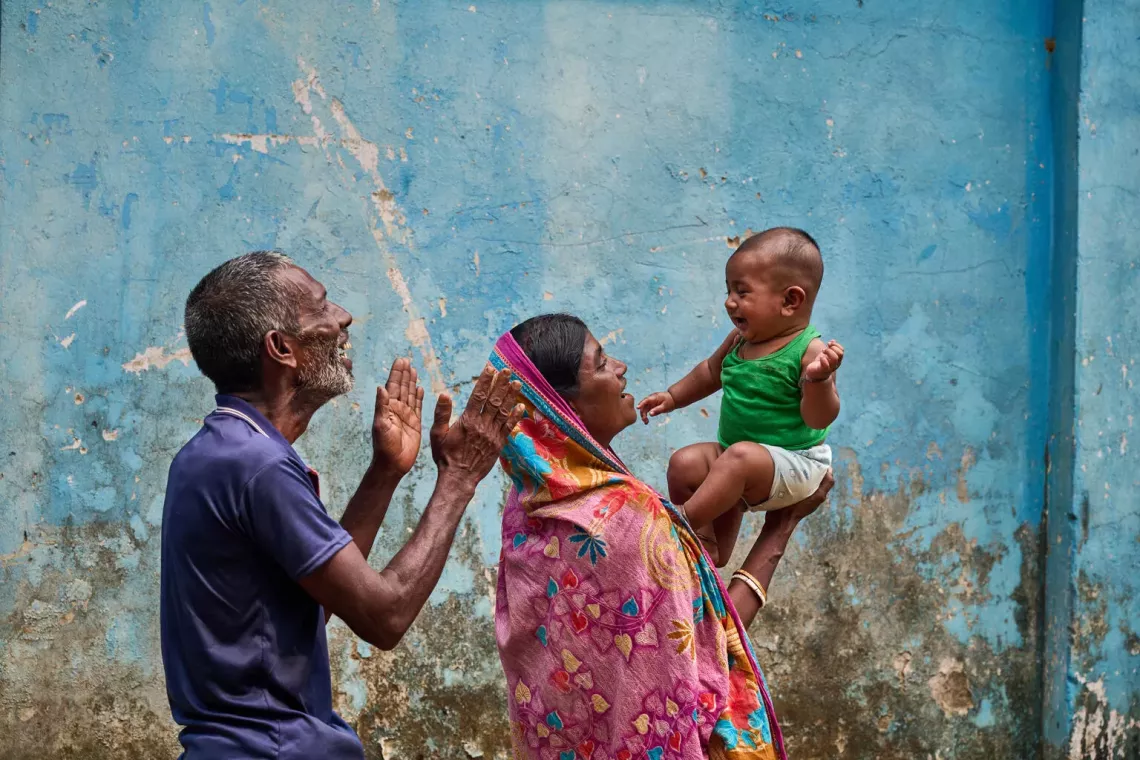 Mother and grandfather work together to keep a child amused while they wait to be seen for vaccination at the community clinic in Tahirpur, Bangladesh. 