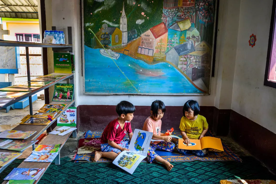 Children read story books written in their ethnic dialect at a UNICEF-supported learning hub in Myanmar. 