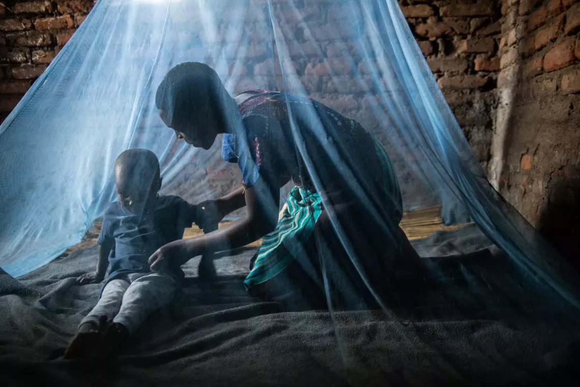 A mother helps her four year old son to sleep under a mosquito net at their home in Nsanje southern Malaw.